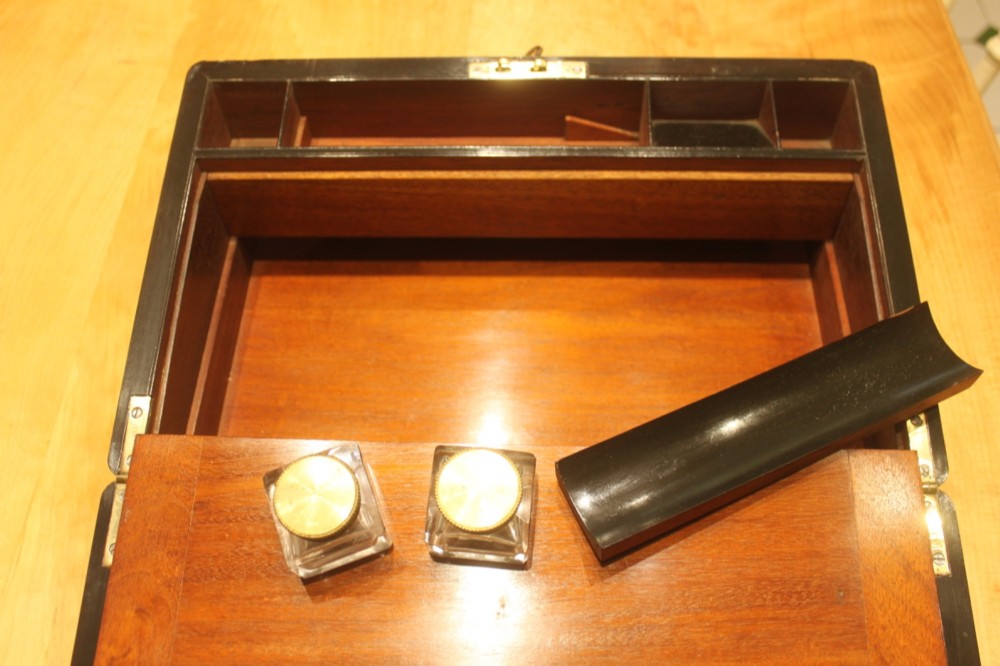 A rectangular curl grain mahogany writing slope box featuring fine brass stringing, brass bound corners, a central brass cartouche, and a keyhole escutcheon. View IX