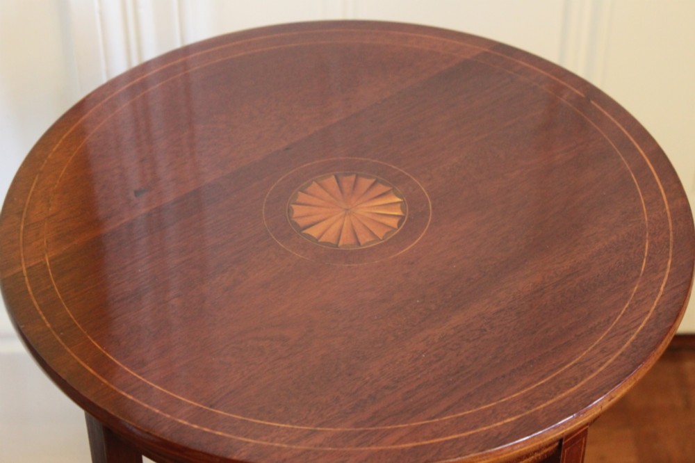 A circular Edwardian mahogany occasional table featuring satinwood starburst inlay and a lower tier on slender splayed legs. View II