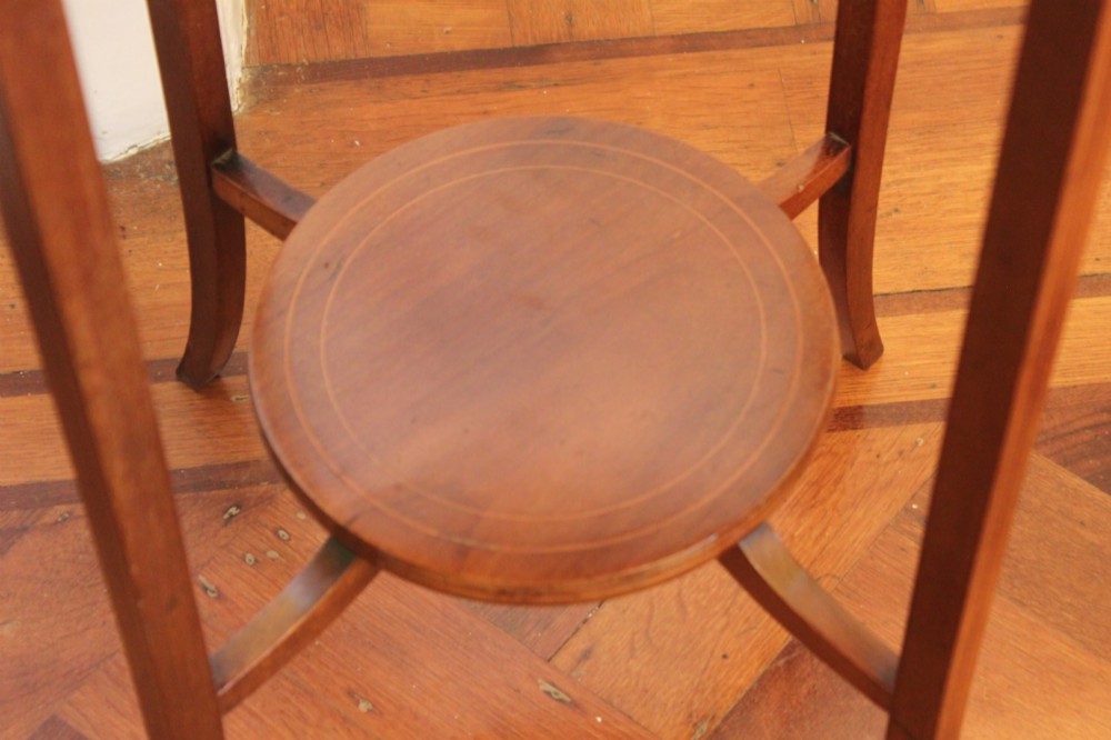 A circular Edwardian mahogany occasional table featuring satinwood starburst inlay and a lower tier on slender splayed legs. View III