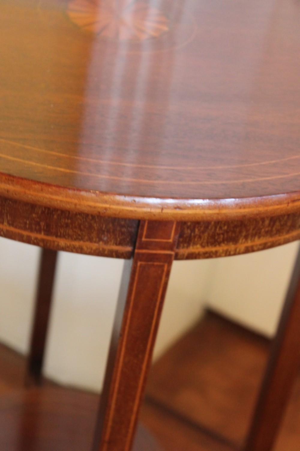 A circular Edwardian mahogany occasional table featuring satinwood starburst inlay and a lower tier on slender splayed legs. View IV