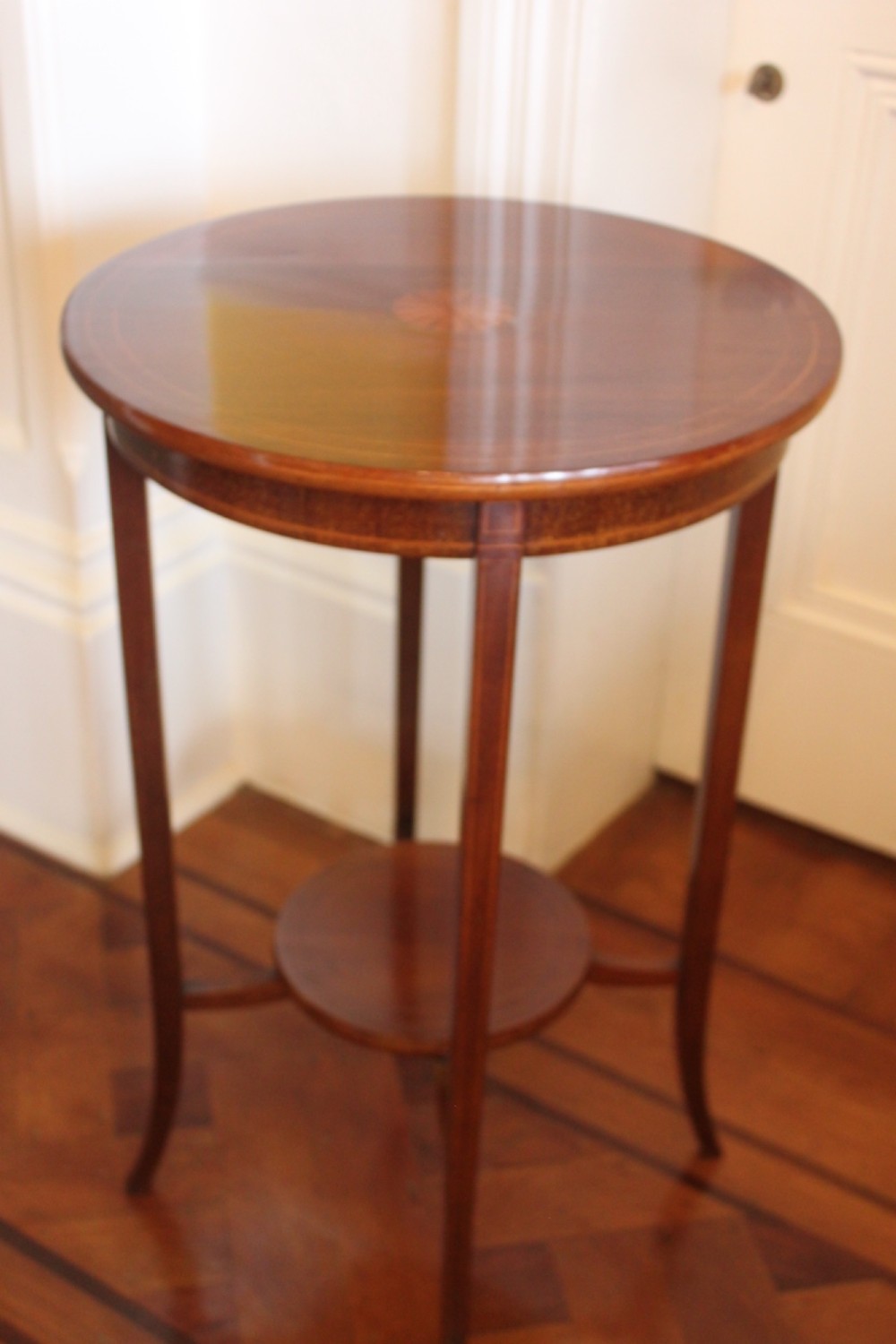 A circular Edwardian mahogany occasional table featuring satinwood starburst inlay and a lower tier on slender splayed legs. View VI