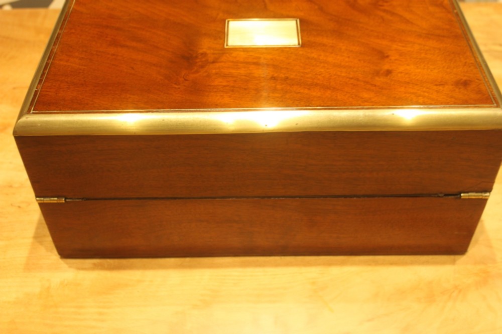 A closed rectangular Victorian walnut writing slope featuring brass binding, an inlaid brass central cartouche, and a keyhole escutcheon with a key. View IV