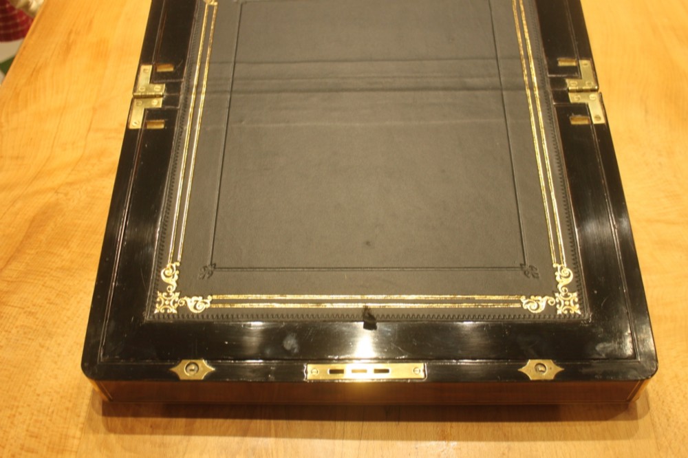A closed rectangular Victorian walnut writing slope featuring brass binding, an inlaid brass central cartouche, and a keyhole escutcheon with a key. View VII
