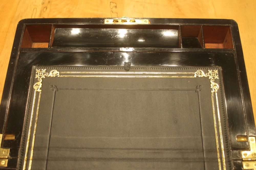 A closed rectangular Victorian walnut writing slope featuring brass binding, an inlaid brass central cartouche, and a keyhole escutcheon with a key. View VIII