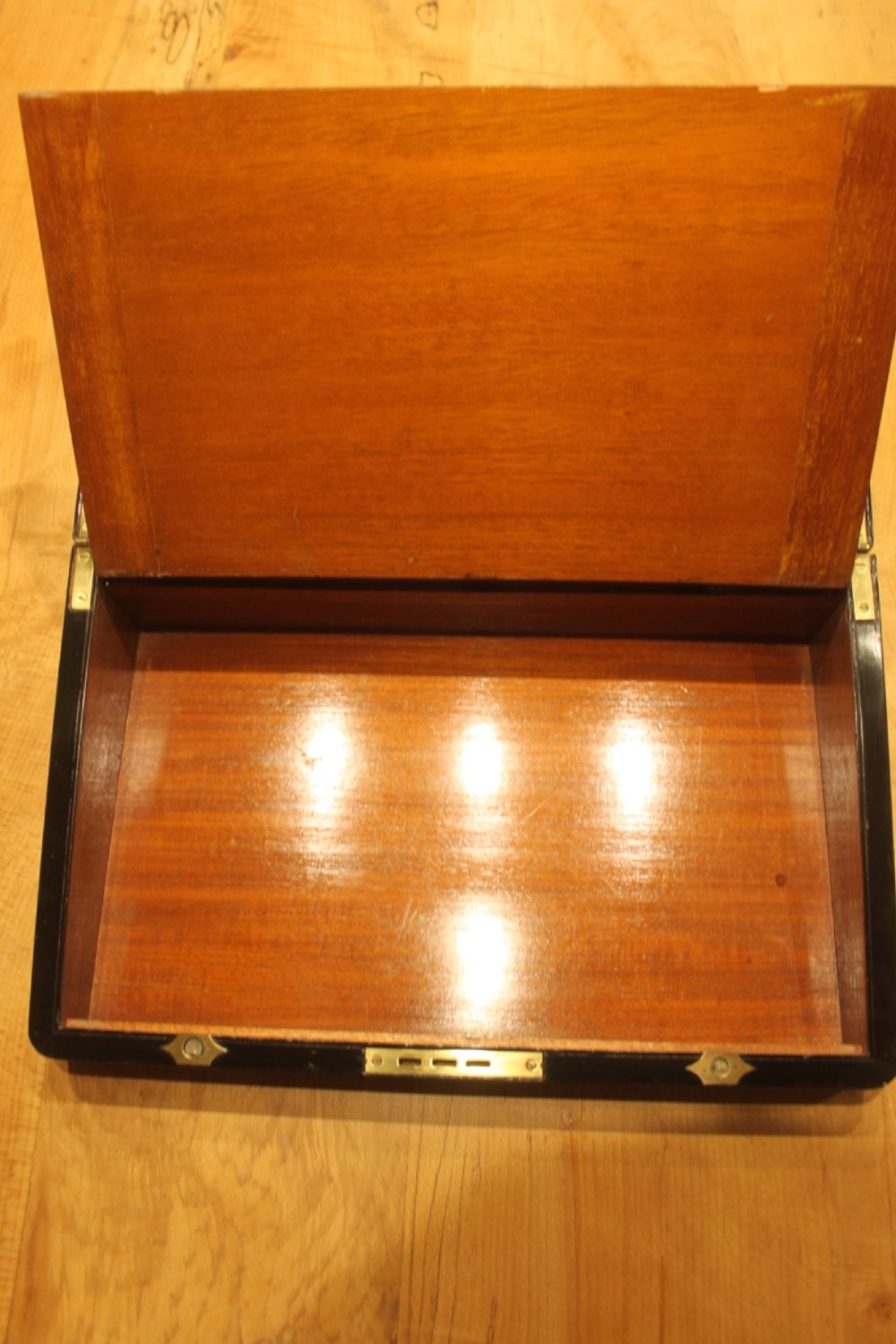 A closed rectangular Victorian walnut writing slope featuring brass binding, an inlaid brass central cartouche, and a keyhole escutcheon with a key. View IX