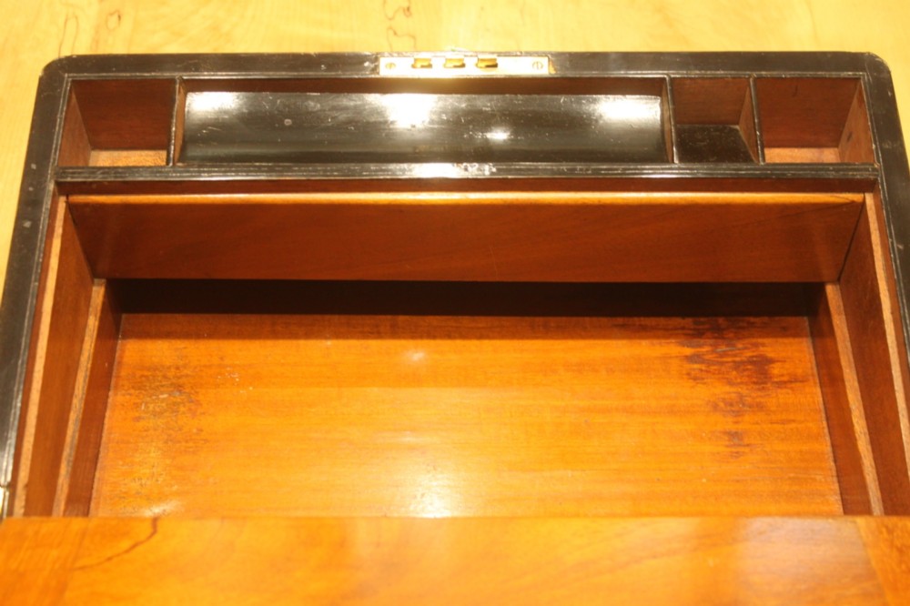 A closed rectangular Victorian walnut writing slope featuring brass binding, an inlaid brass central cartouche, and a keyhole escutcheon with a key. View X