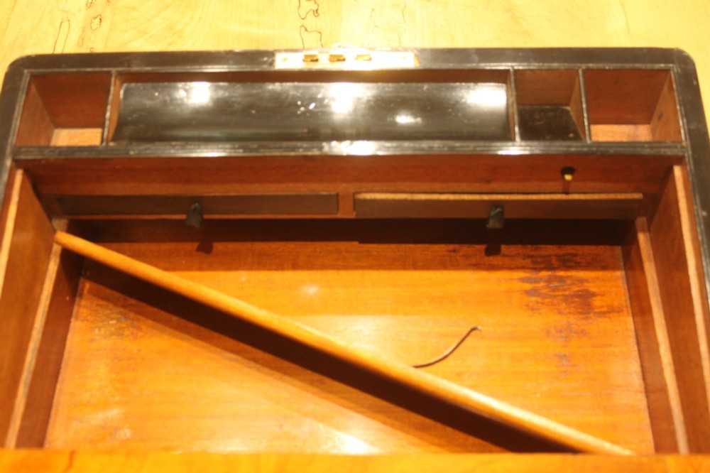 A closed rectangular Victorian walnut writing slope featuring brass binding, an inlaid brass central cartouche, and a keyhole escutcheon with a key. View XI