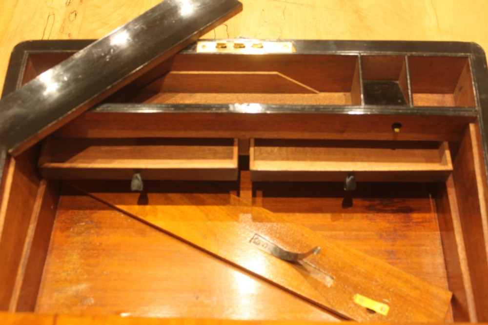 A closed rectangular Victorian walnut writing slope featuring brass binding, an inlaid brass central cartouche, and a keyhole escutcheon with a key. View XII