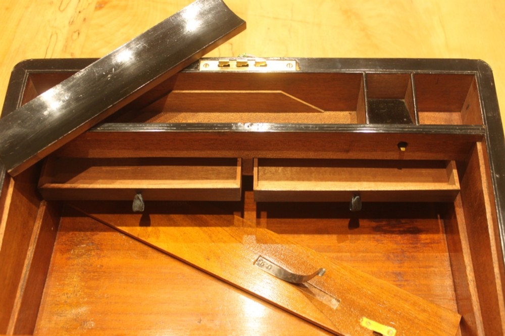 A closed rectangular Victorian walnut writing slope featuring brass binding, an inlaid brass central cartouche, and a keyhole escutcheon with a key. View XIII