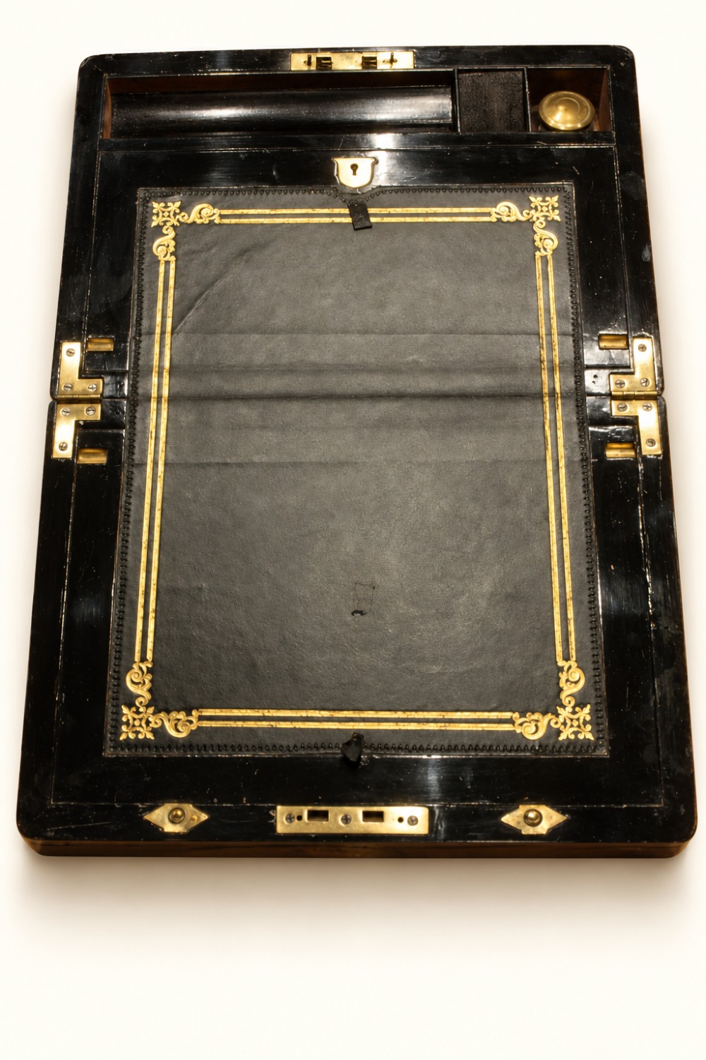 A rectangular Victorian rosewood writing slope featuring brass-bound edges, an inlaid central brass plaque, and a key with a tassel in a brass Bramah lock. View V