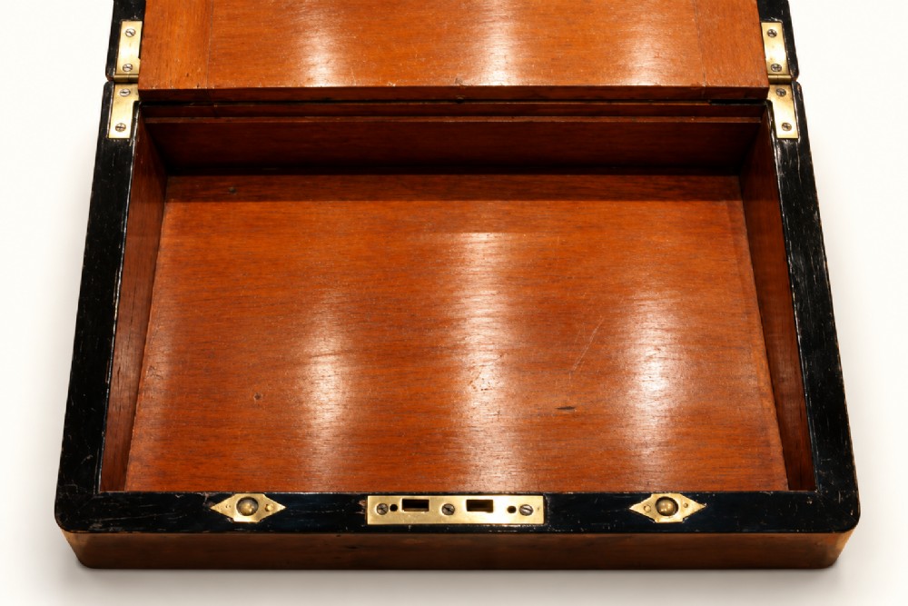 A rectangular Victorian rosewood writing slope featuring brass-bound edges, an inlaid central brass plaque, and a key with a tassel in a brass Bramah lock. View VI