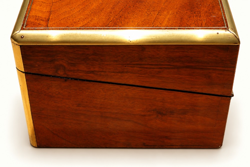 A rectangular Victorian walnut writing slope box featuring polished brass edge binding, a central brass inlaid plaque, and a key inserted into the front lock. View IV