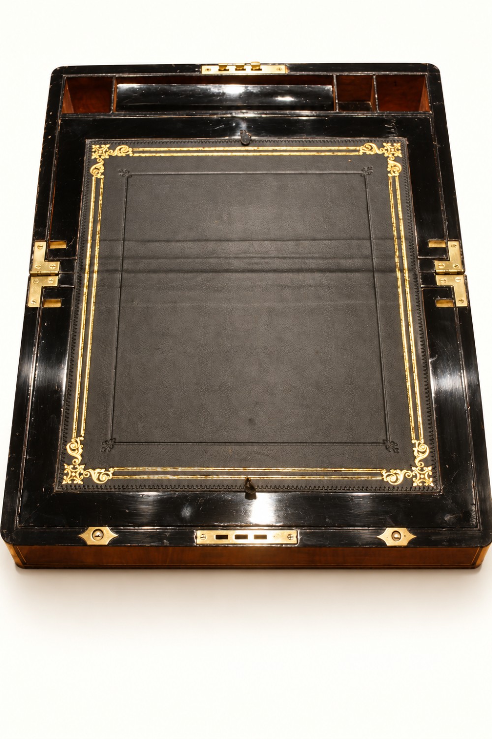 A rectangular Victorian walnut writing slope box featuring polished brass edge binding, a central brass inlaid plaque, and a key inserted into the front lock. View V