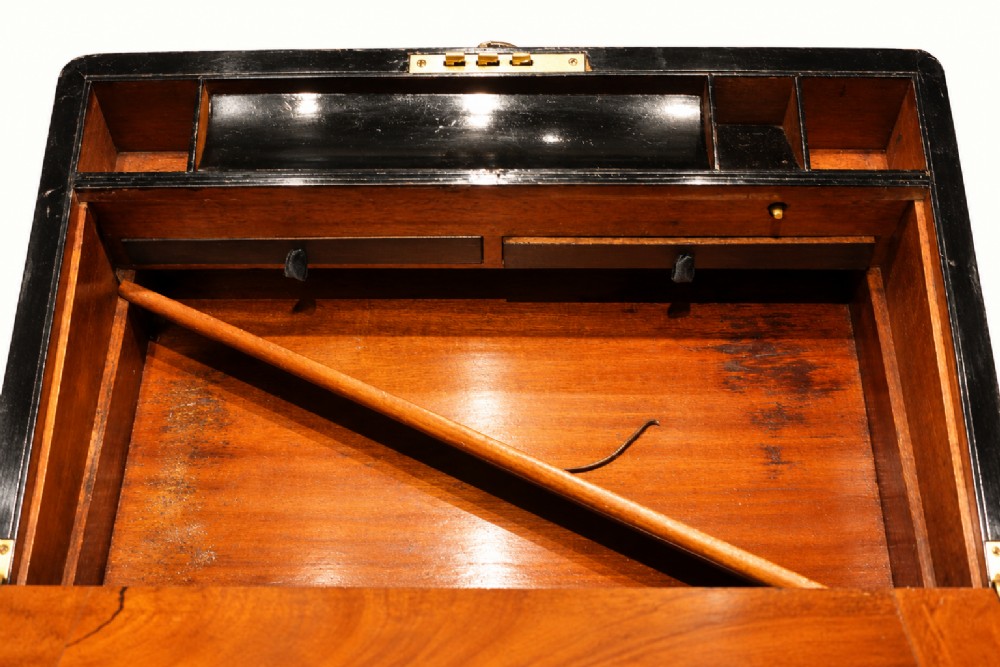 A rectangular Victorian walnut writing slope box featuring polished brass edge binding, a central brass inlaid plaque, and a key inserted into the front lock. View X