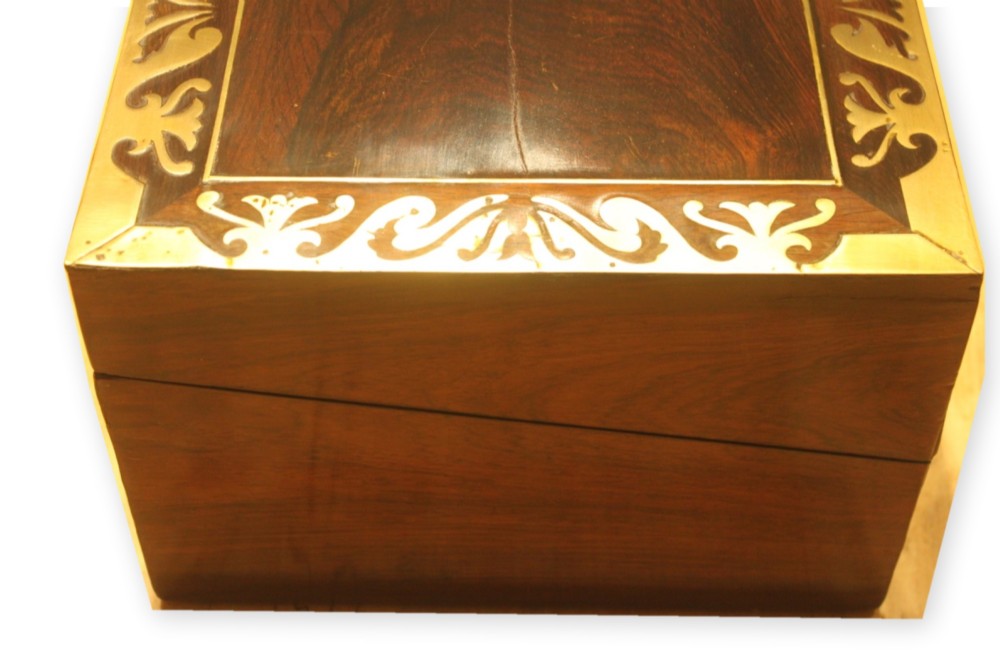 A closed rectangular dark rosewood writing slope box featuring detailed brass foliate inlay along the borders and a brass key inserted into the front lock. View IV