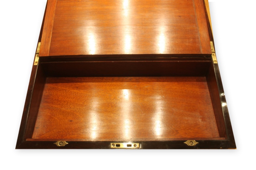 A closed rectangular dark rosewood writing slope box featuring detailed brass foliate inlay along the borders and a brass key inserted into the front lock. View VII