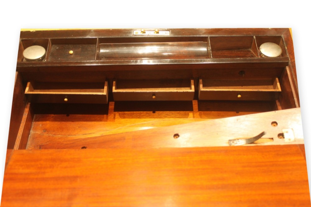 A closed rectangular dark rosewood writing slope box featuring detailed brass foliate inlay along the borders and a brass key inserted into the front lock. View X