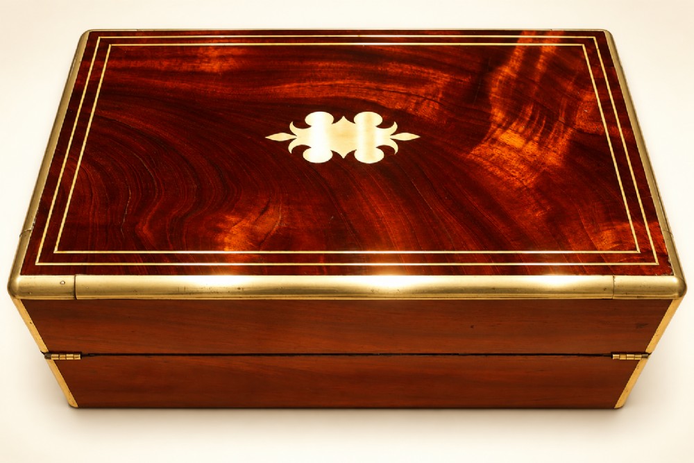 An antique curl grain mahogany writing slope with fine brass stringing inlay, a decorative central brass cartouche, and a brass key inserted in the escutcheon. View III
