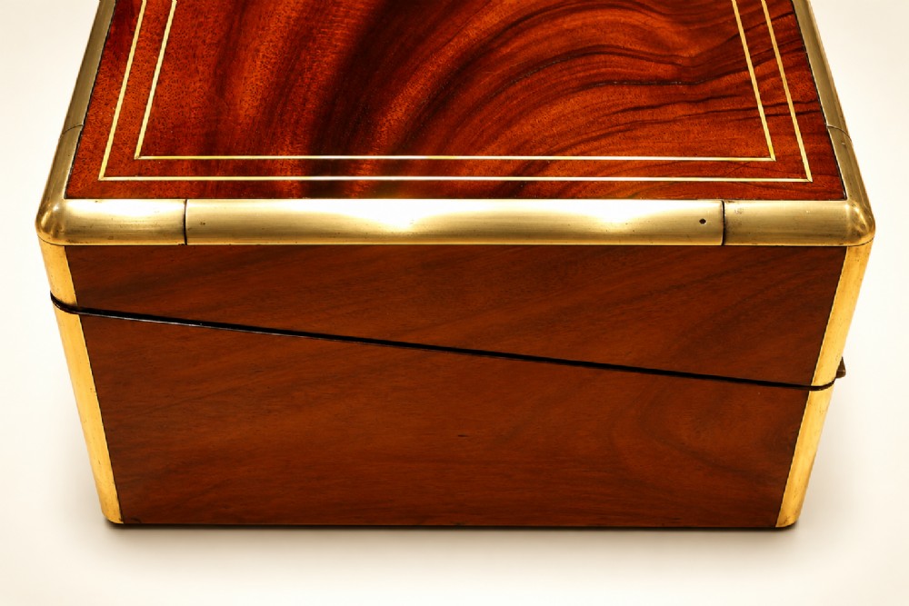 An antique curl grain mahogany writing slope with fine brass stringing inlay, a decorative central brass cartouche, and a brass key inserted in the escutcheon. View IV