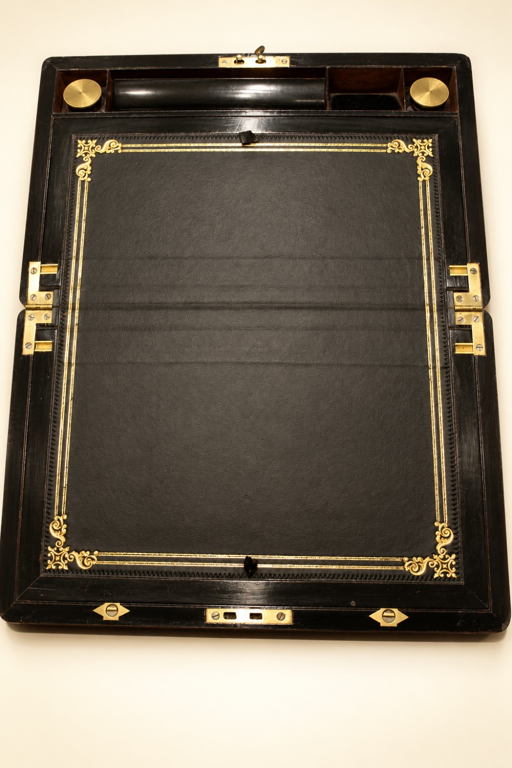 An antique curl grain mahogany writing slope with fine brass stringing inlay, a decorative central brass cartouche, and a brass key inserted in the escutcheon. View V