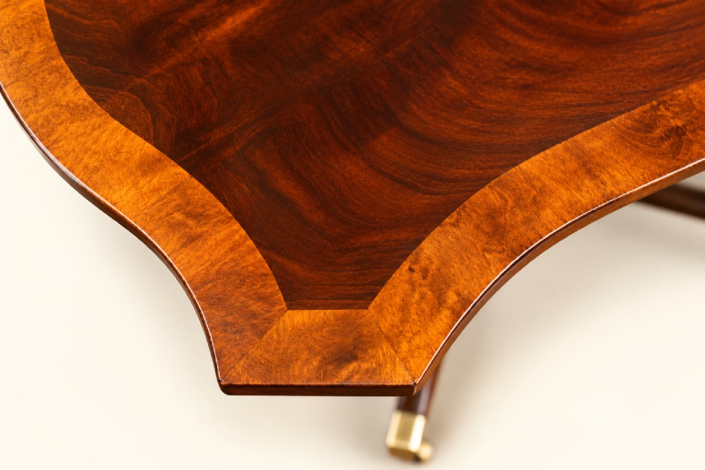 A 19th-century mahogany occasional table featuring a serpentine-shaped tilt top with decorative crossbanding, a turned pedestal base, and four splayed legs ending in brass toe caps. View II
