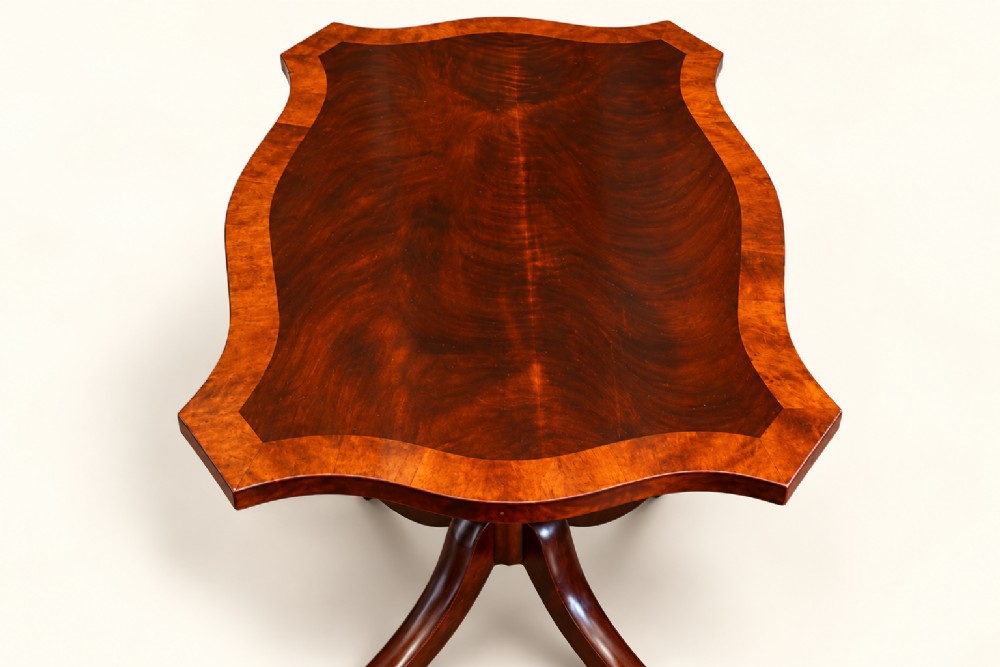 A 19th-century mahogany occasional table featuring a serpentine-shaped tilt top with decorative crossbanding, a turned pedestal base, and four splayed legs ending in brass toe caps. View III