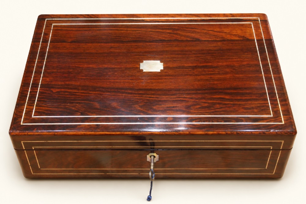 A rectangular dark rosewood wooden writing slope featuring double brass stringing inlay, a central brass cartouche, and an escutcheon with an inserted key. View II