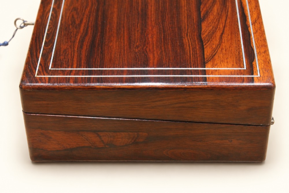 A rectangular dark rosewood wooden writing slope featuring double brass stringing inlay, a central brass cartouche, and an escutcheon with an inserted key. View V