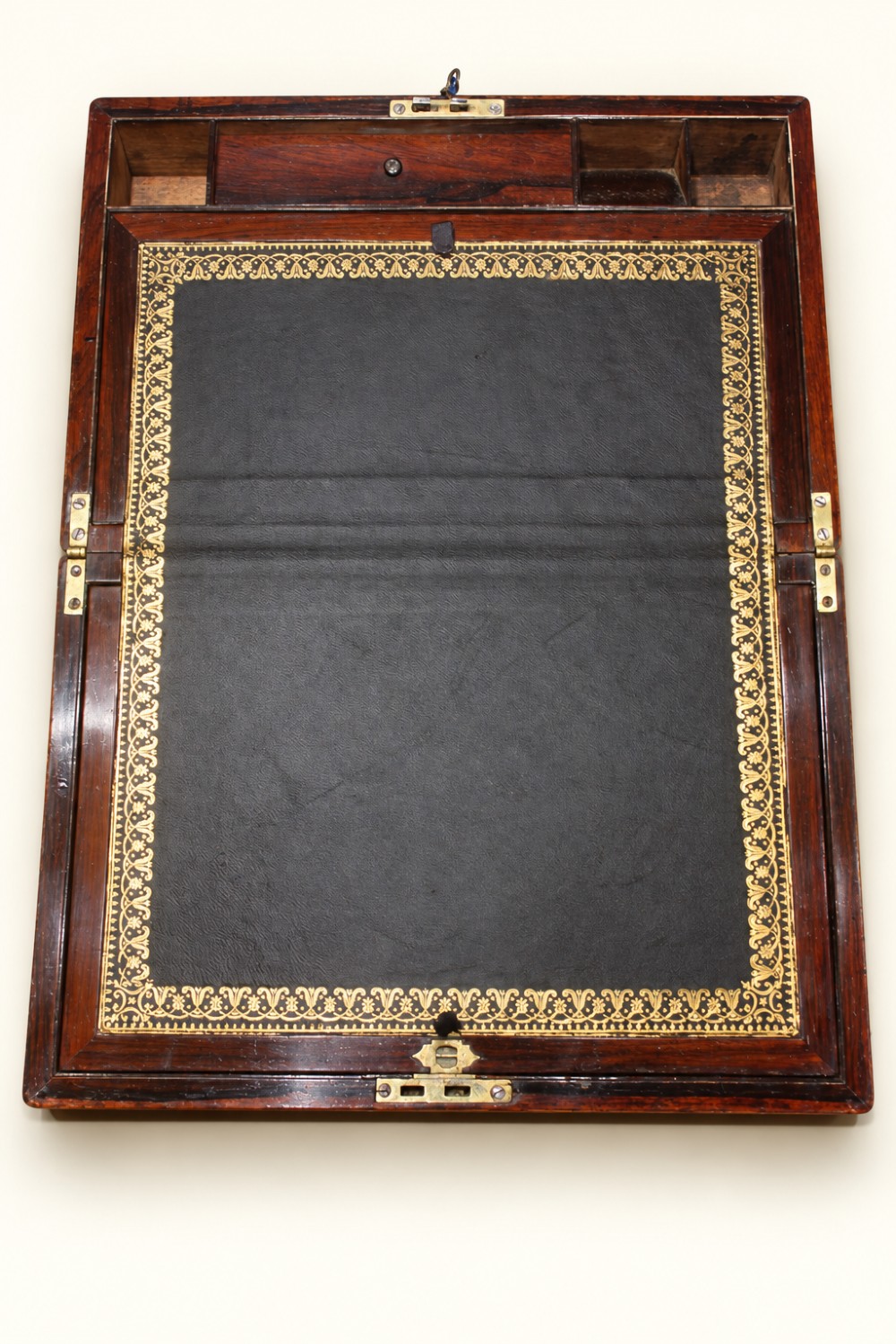 A rectangular dark rosewood wooden writing slope featuring double brass stringing inlay, a central brass cartouche, and an escutcheon with an inserted key. View VI