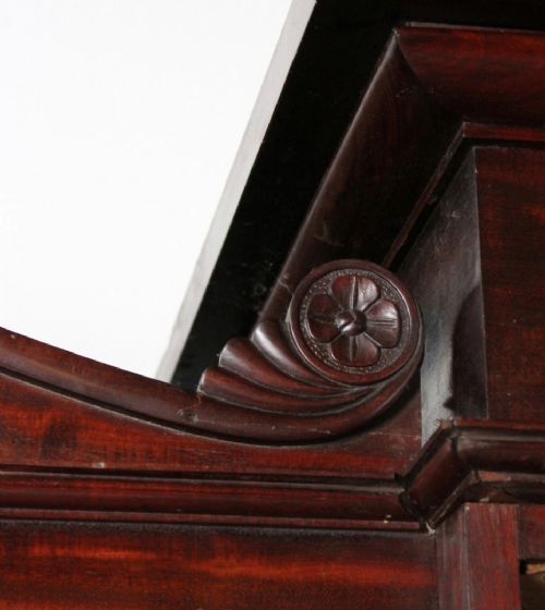 A nineteenth-century Victorian flame mahogany breakfront compactum wardrobe featuring a central chest of drawers flanked by two arched-panel cupboard doors beneath a carved central cresting. View IV