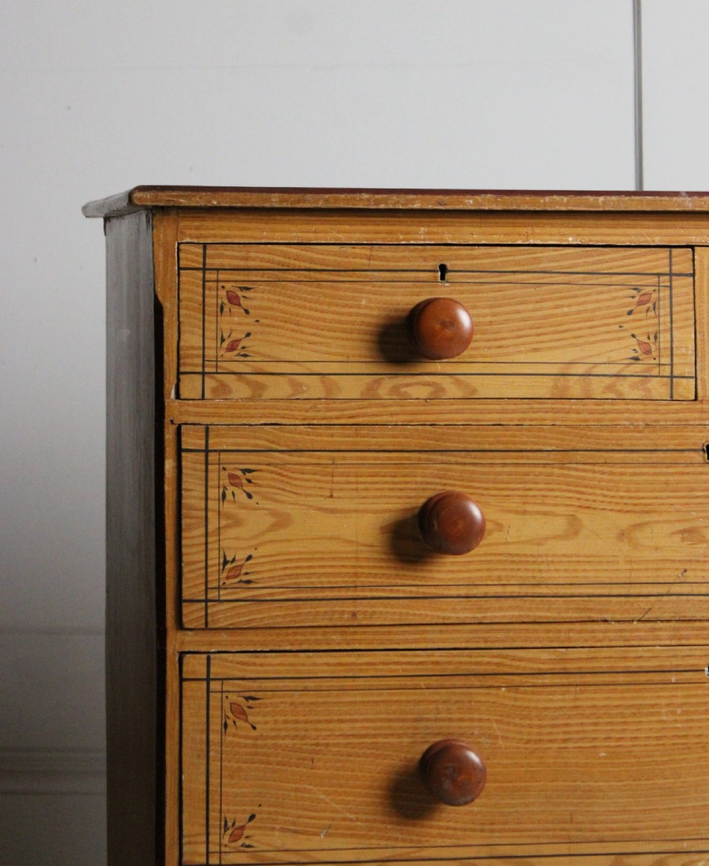 A 19th-century pine chest of drawers with a warm brown scumbled paint finish, featuring two short drawers over three long drawers with turned wooden knobs. View II