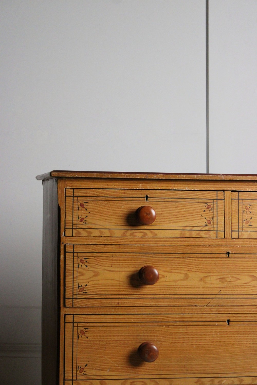 A 19th-century pine chest of drawers with a warm brown scumbled paint finish, featuring two short drawers over three long drawers with turned wooden knobs. View III