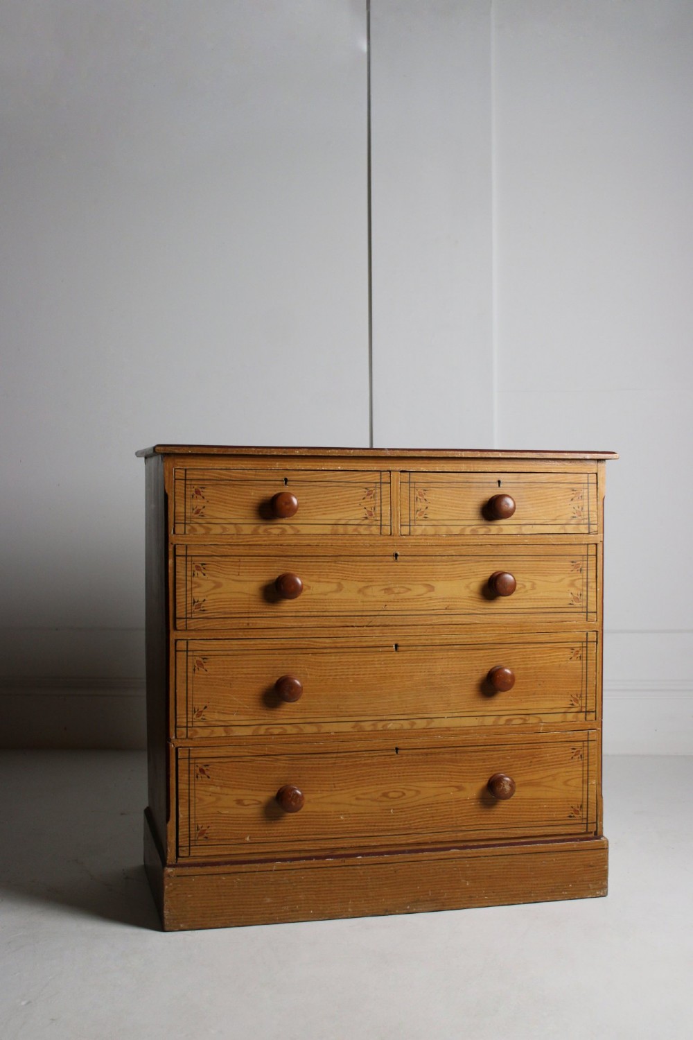 A 19th-century pine chest of drawers with a warm brown scumbled paint finish, featuring two short drawers over three long drawers with turned wooden knobs. View IV