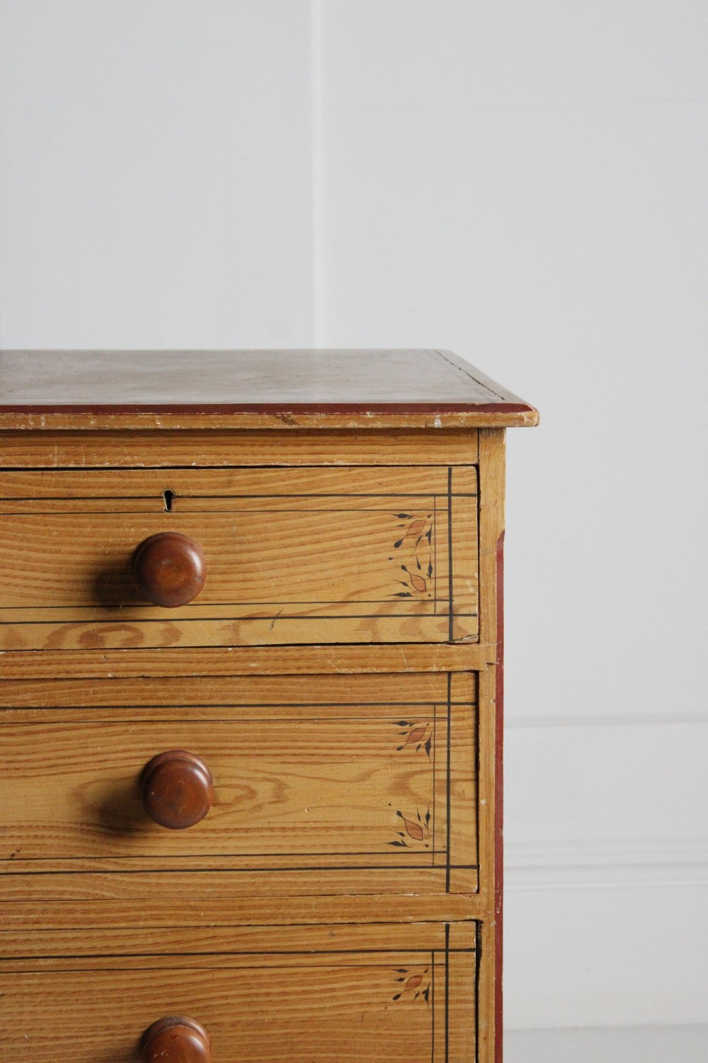 A 19th-century pine chest of drawers with a warm brown scumbled paint finish, featuring two short drawers over three long drawers with turned wooden knobs. View V