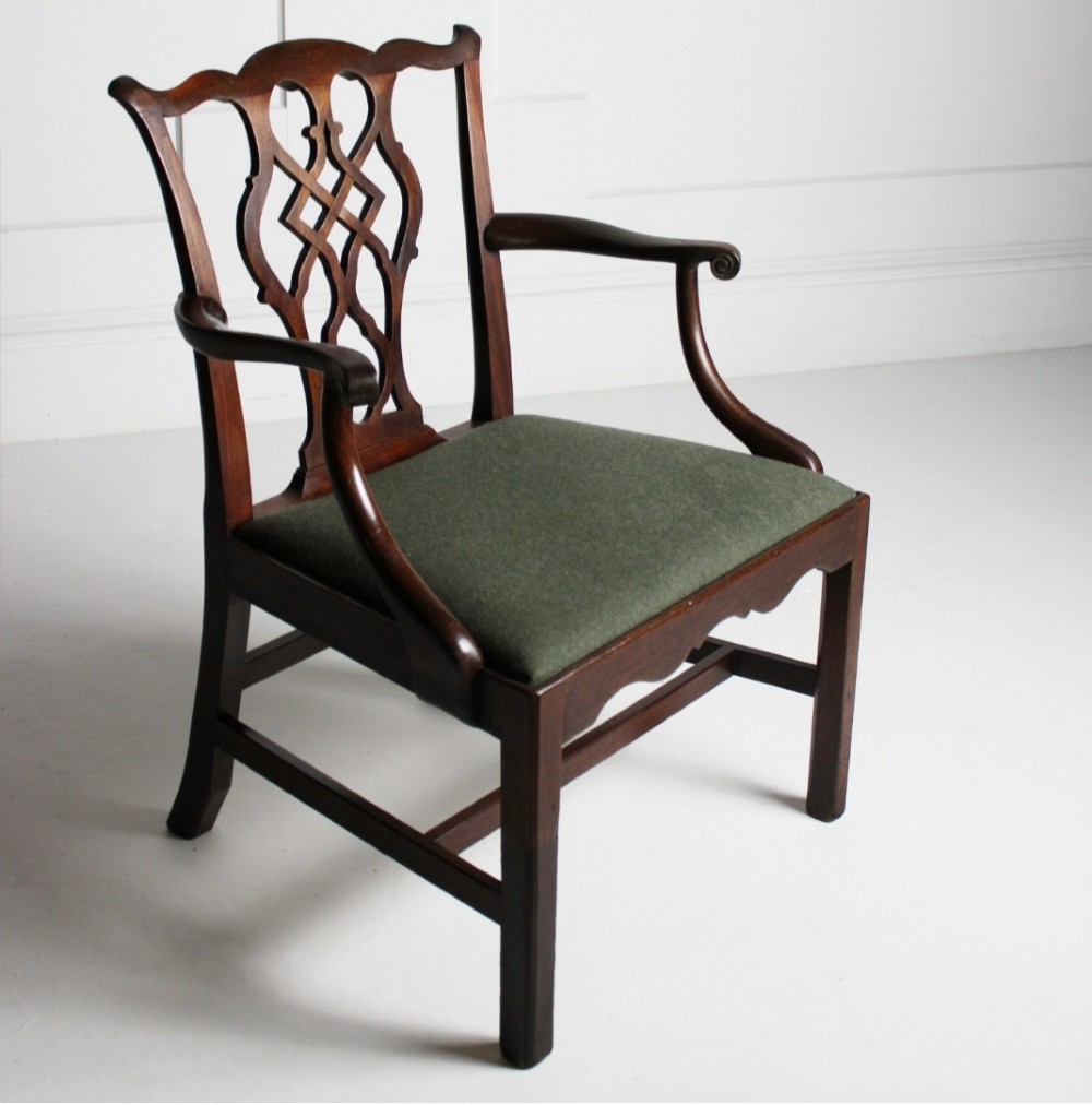 A Georgian dark mahogany open armchair featuring a pierced lattice back splat, curved arms, and a green upholstered seat.