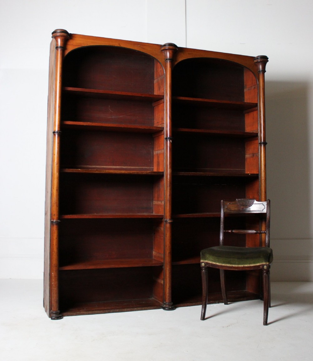 A large 19th-century double-bay open timber bookcase with arched tops and turned column pilasters in a warm brown finish.