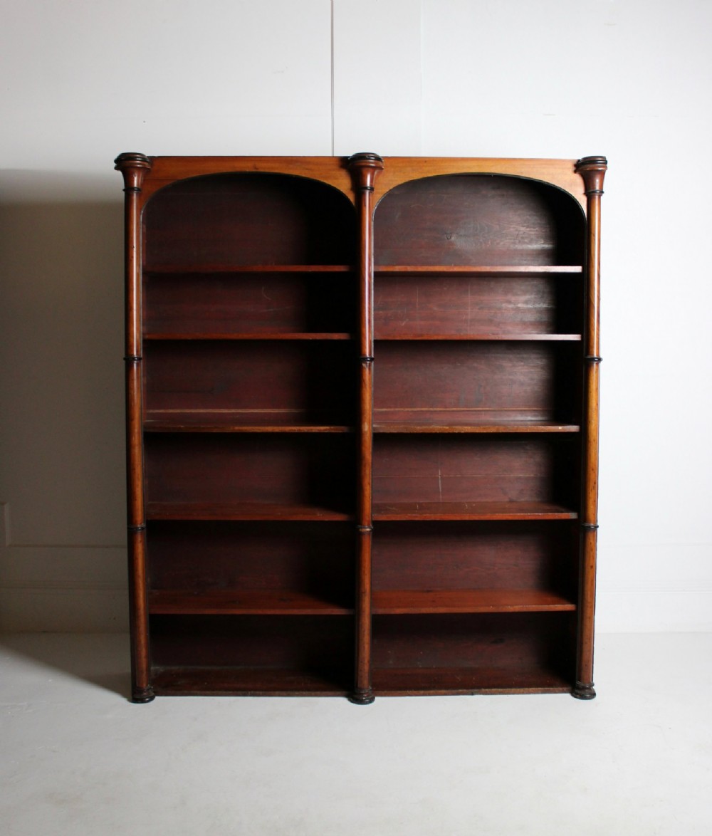 A large 19th-century double-bay open timber bookcase with arched tops and turned column pilasters in a warm brown finish. View V