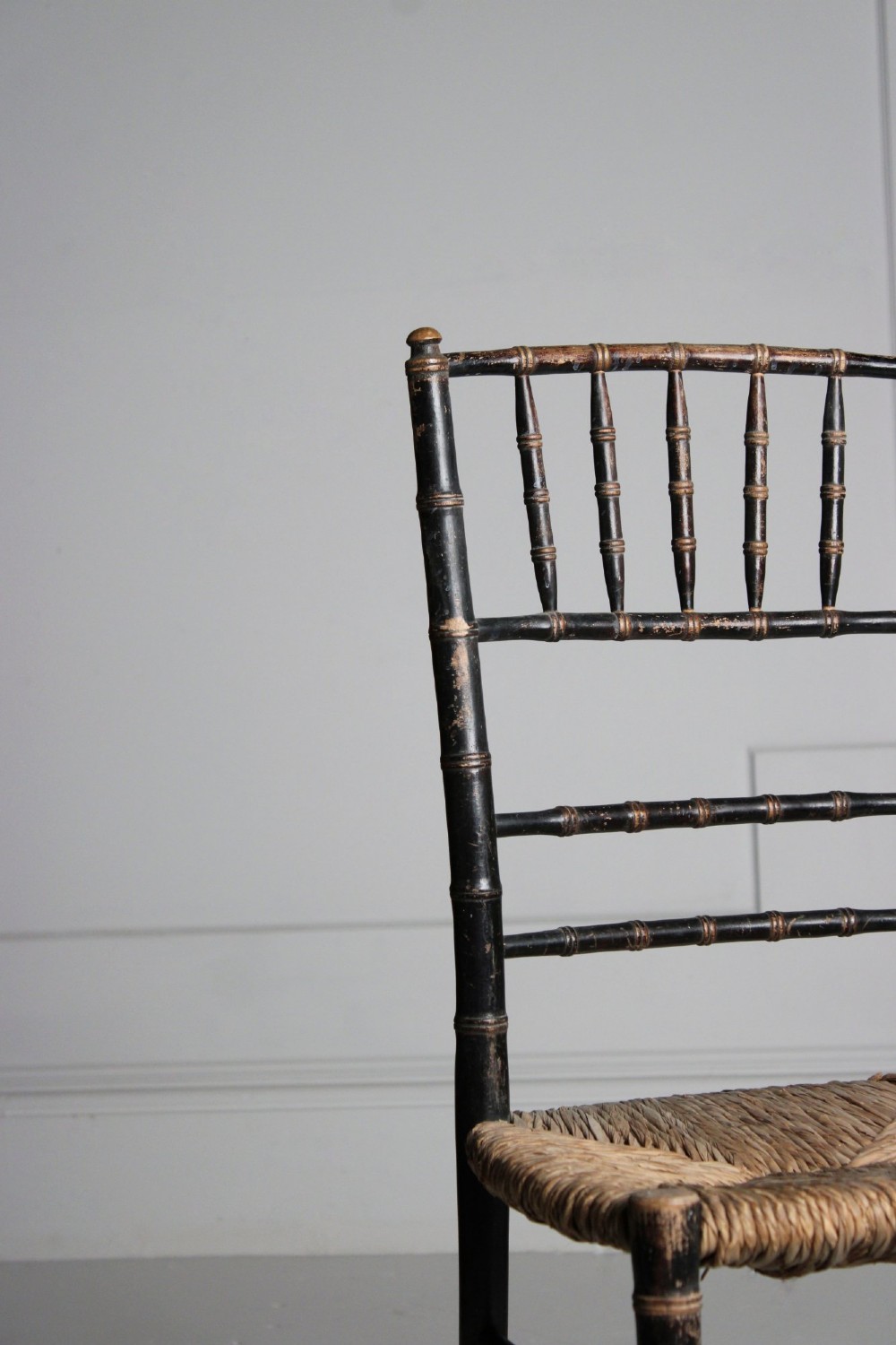 A late 19th-century ebonised side chair featuring turned faux bamboo detailing and a woven rush seat. View II