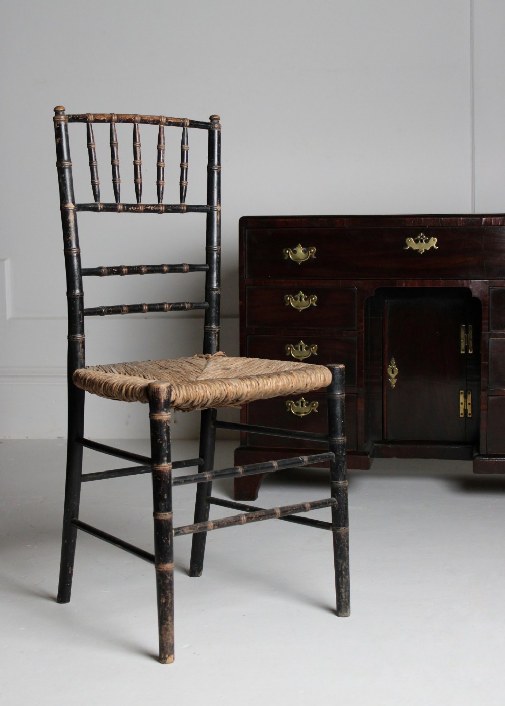 A late 19th-century ebonised side chair featuring turned faux bamboo detailing and a woven rush seat.