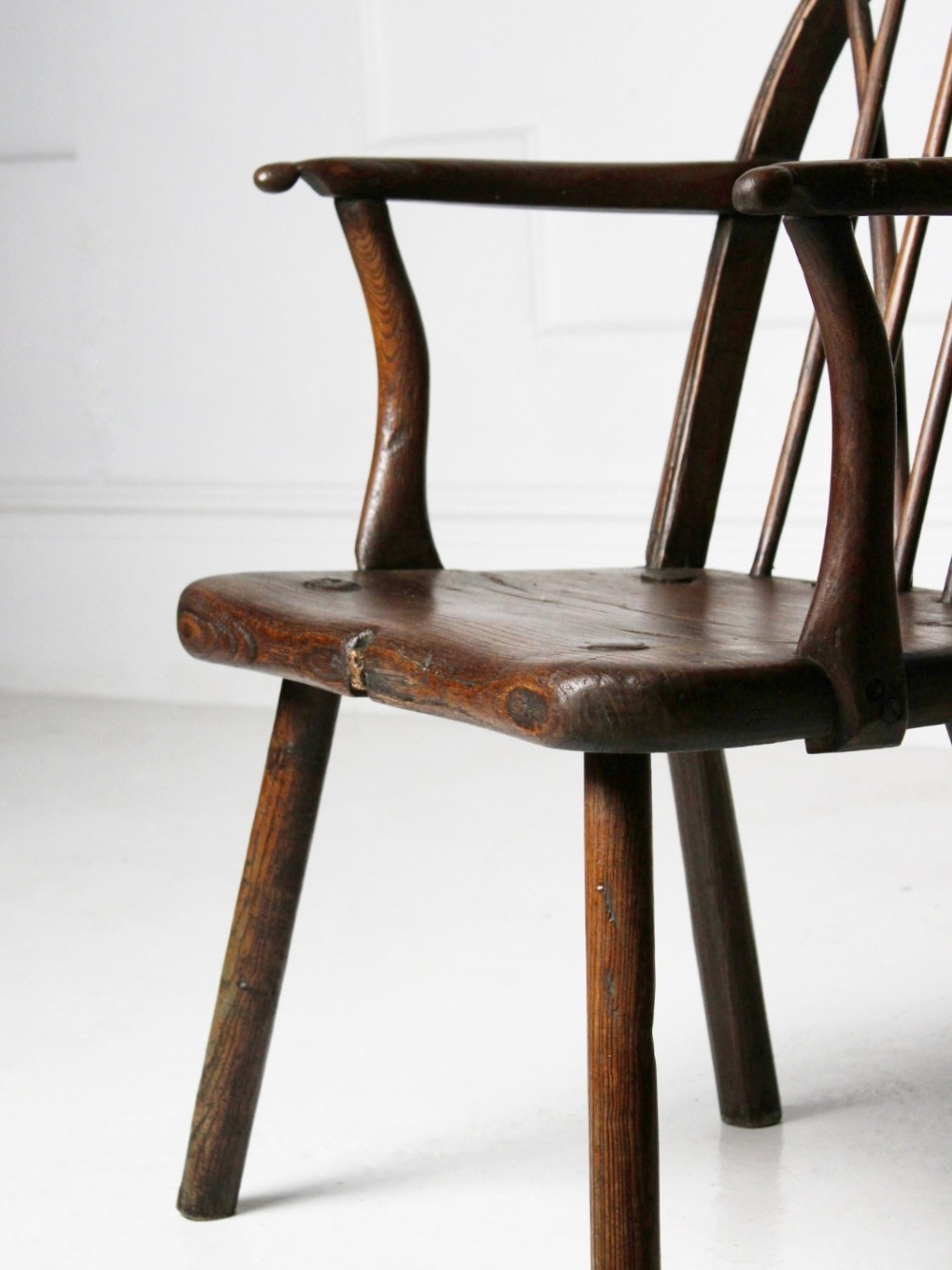 An 18th-century vernacular dark wooden armchair featuring a stick back design, curved armrests, a solid slab seat, and splayed legs. View II