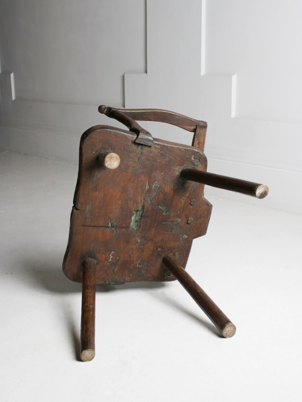 An 18th-century vernacular dark wooden armchair featuring a stick back design, curved armrests, a solid slab seat, and splayed legs. View III