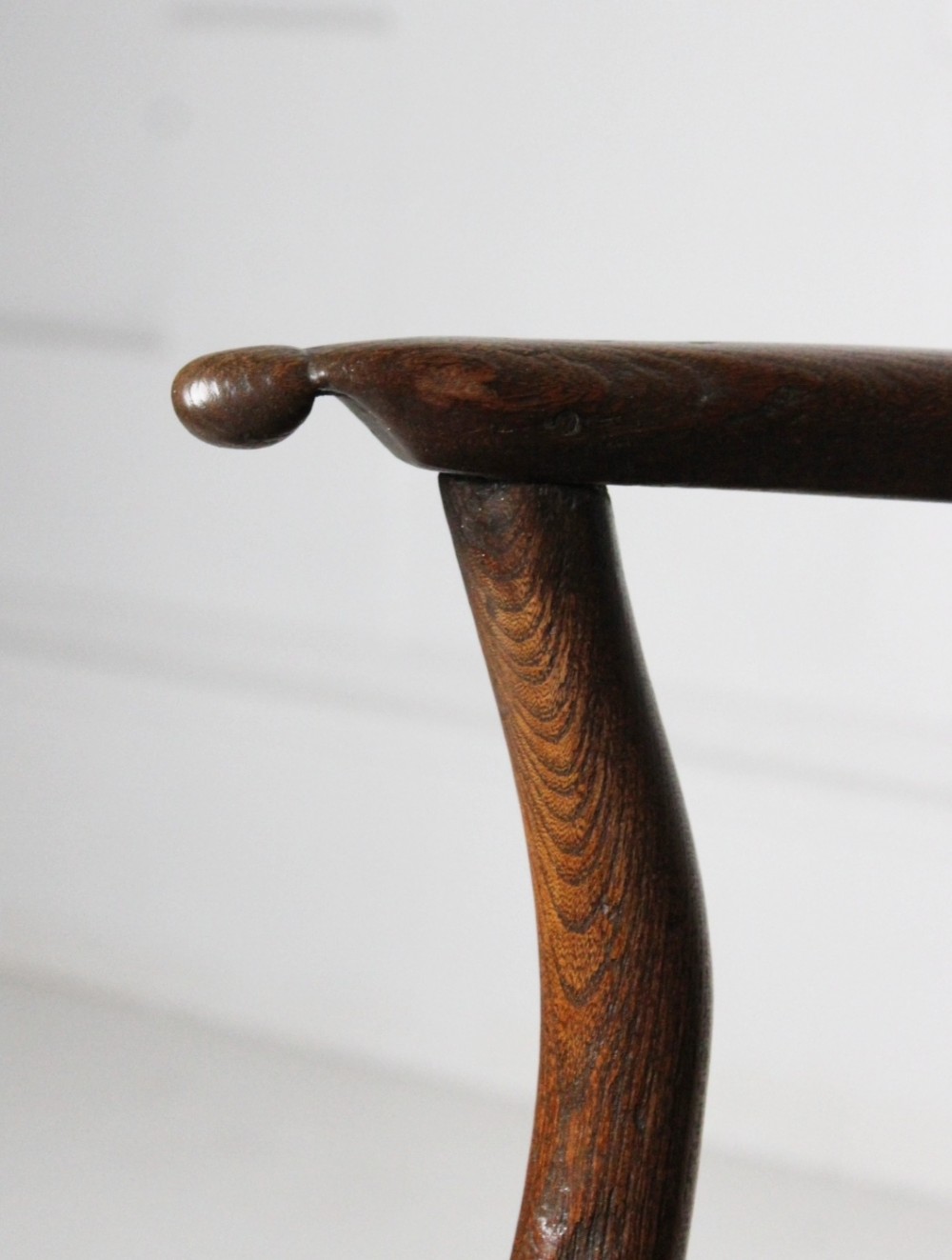 An 18th-century vernacular dark wooden armchair featuring a stick back design, curved armrests, a solid slab seat, and splayed legs. View IV