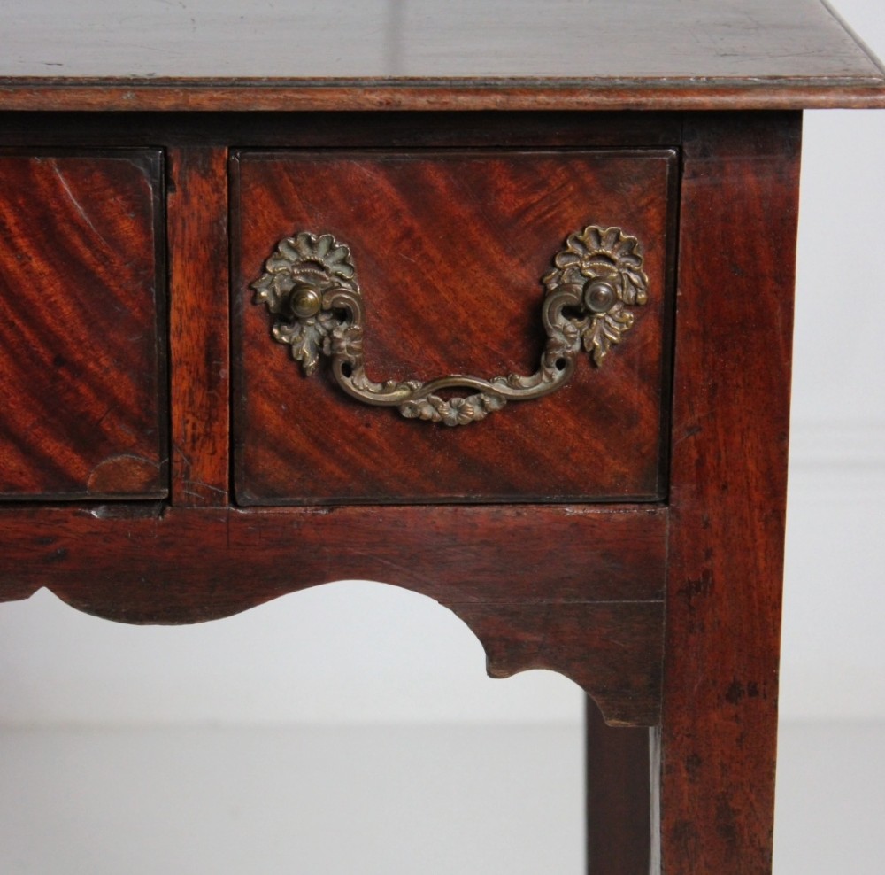 An 18th-century Georgian mahogany side table with three frieze drawers, brass swan-neck handles, a shaped apron, and tapered square legs. View VI