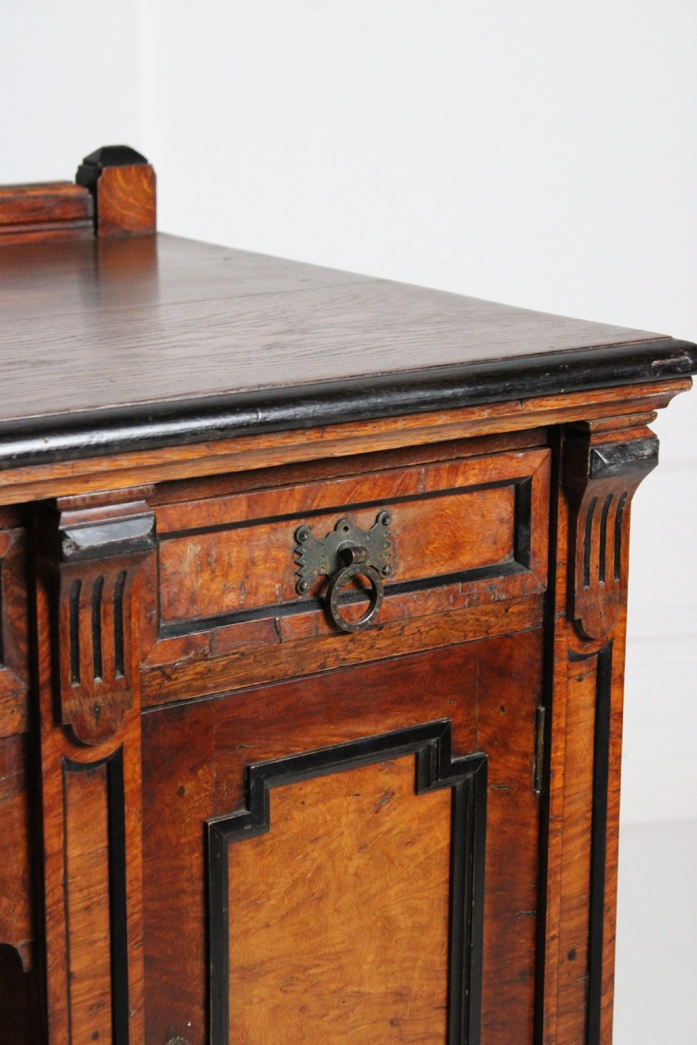 An Aesthetic Movement kneehole writing desk in walnut with ebonised borders, three upper drawers, two pedestal cupboards, and brass ring handles. View III