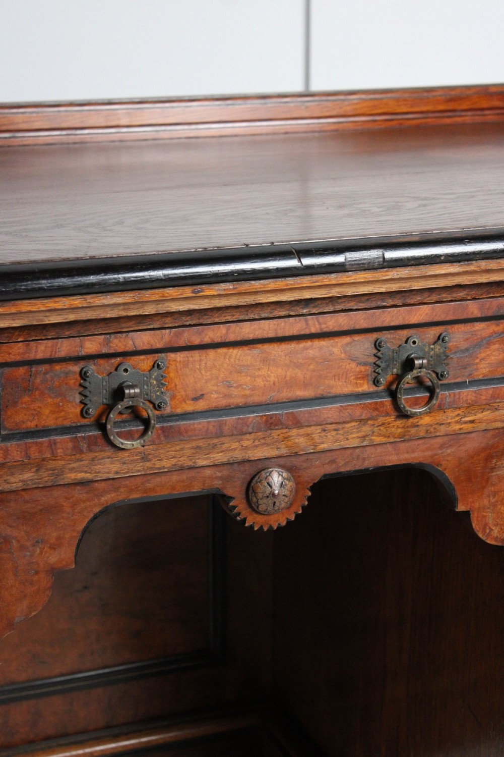 An Aesthetic Movement kneehole writing desk in walnut with ebonised borders, three upper drawers, two pedestal cupboards, and brass ring handles. View IV