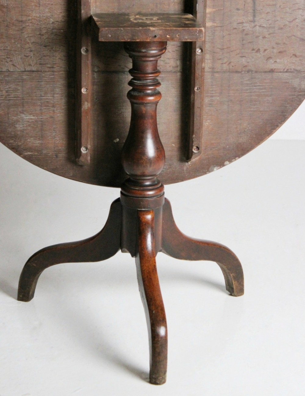 An 18th-century circular oak tilt-top table shown in a vertically tilted position on a turned tripod base. View II