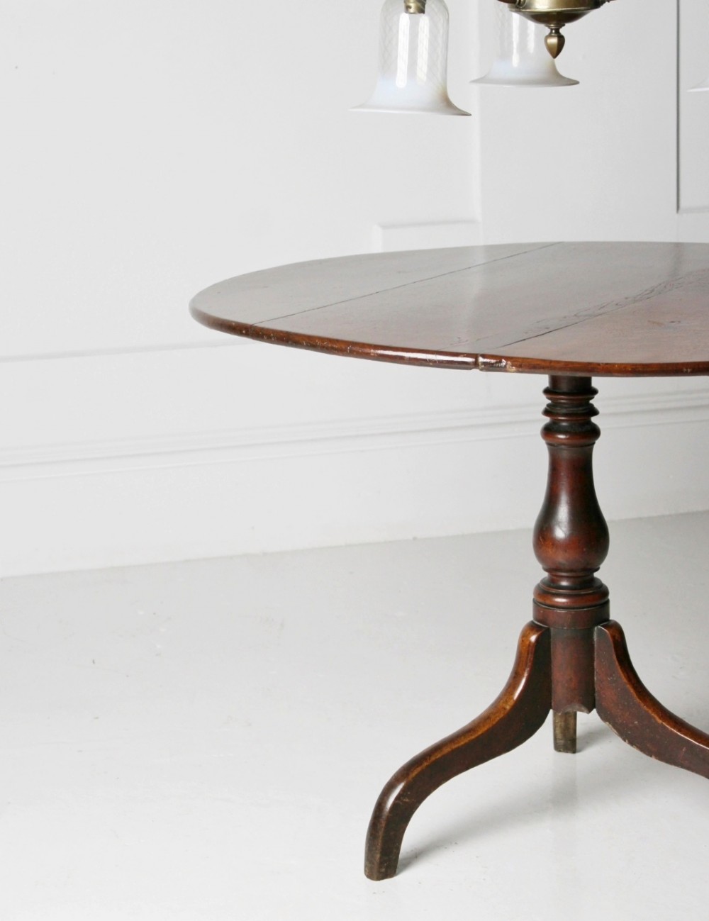 An 18th-century circular oak tilt-top table shown in a vertically tilted position on a turned tripod base. View III