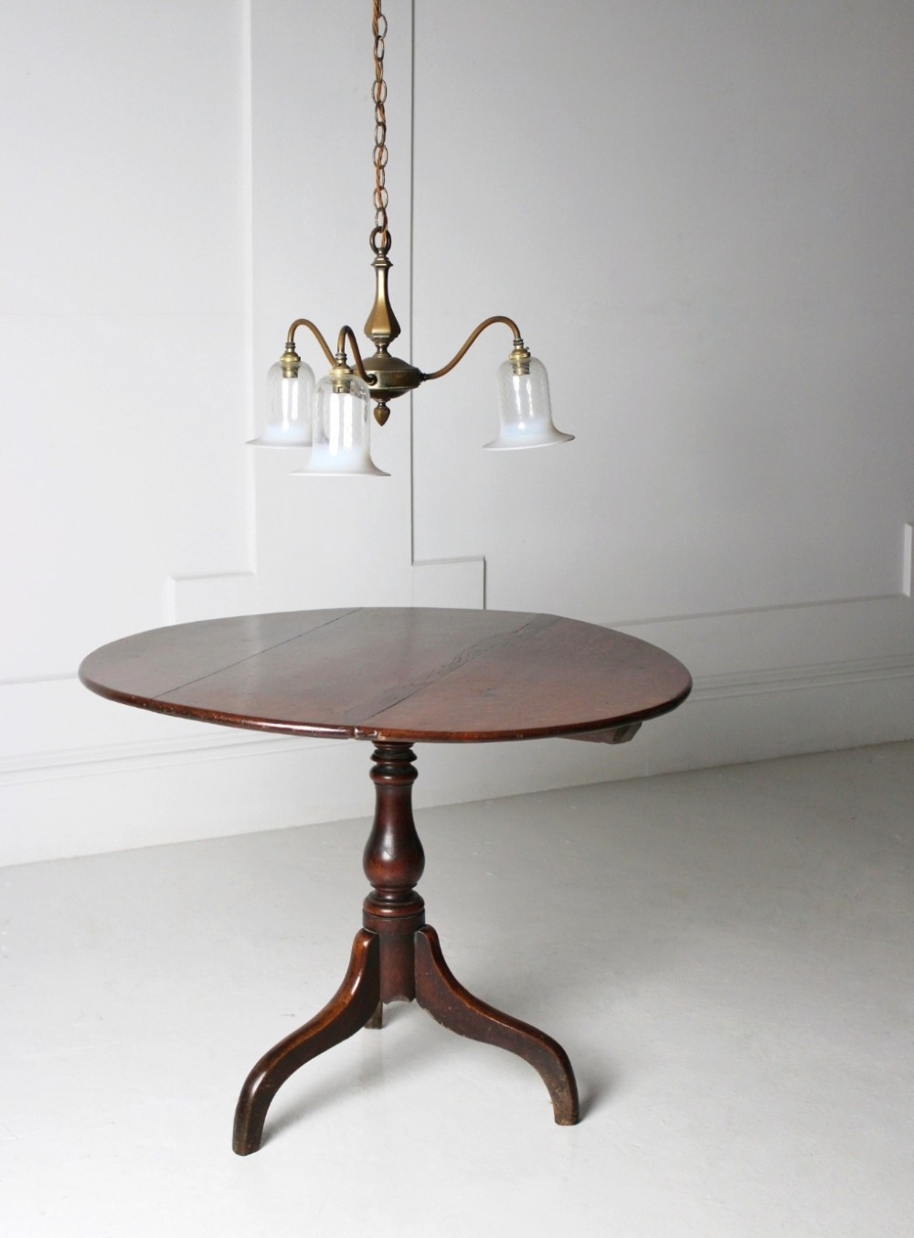 An 18th-century circular oak tilt-top table shown in a vertically tilted position on a turned tripod base. View IV