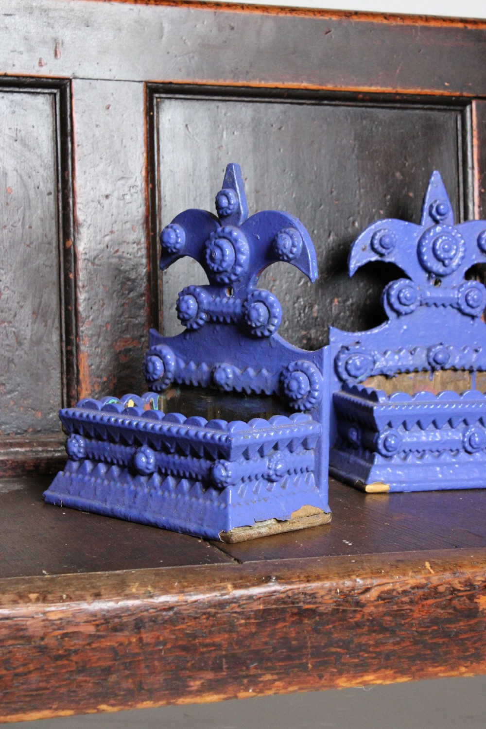 A pair of notch-carved wooden tramp art wall boxes painted in vivid blue with geometric chip-carved layers and crown pediments. View VI