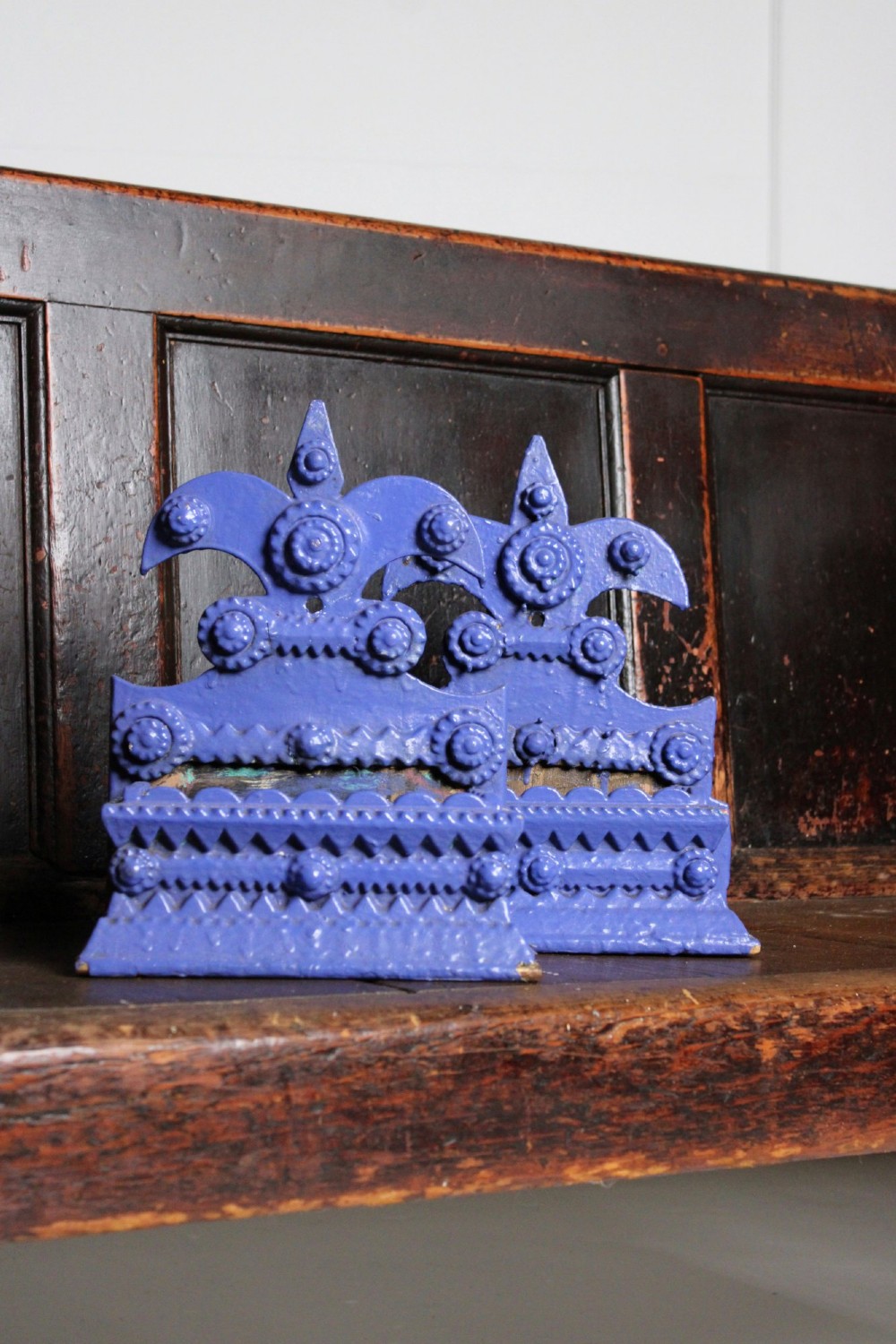 A pair of notch-carved wooden tramp art wall boxes painted in vivid blue with geometric chip-carved layers and crown pediments.
